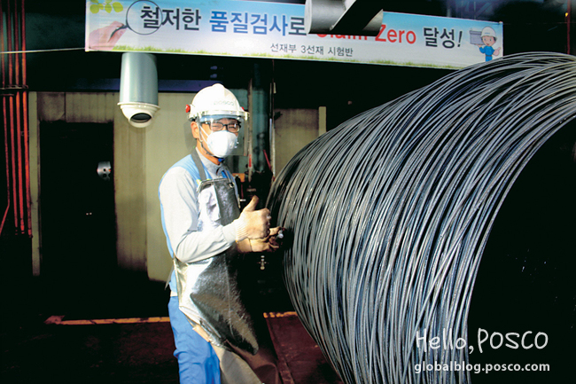 An employee at Pohang 3rd Wire Rod Factory gives a thumb-up while checking flaws on 200℃ hot coils