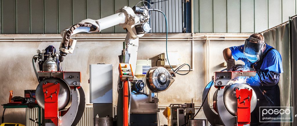 A welder gets help from a cobot as he pieces together metal
