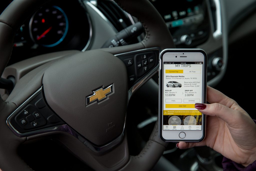 A person inside a GM vehicle is showing Maven, a new car sharing service, on her smartphone screen.