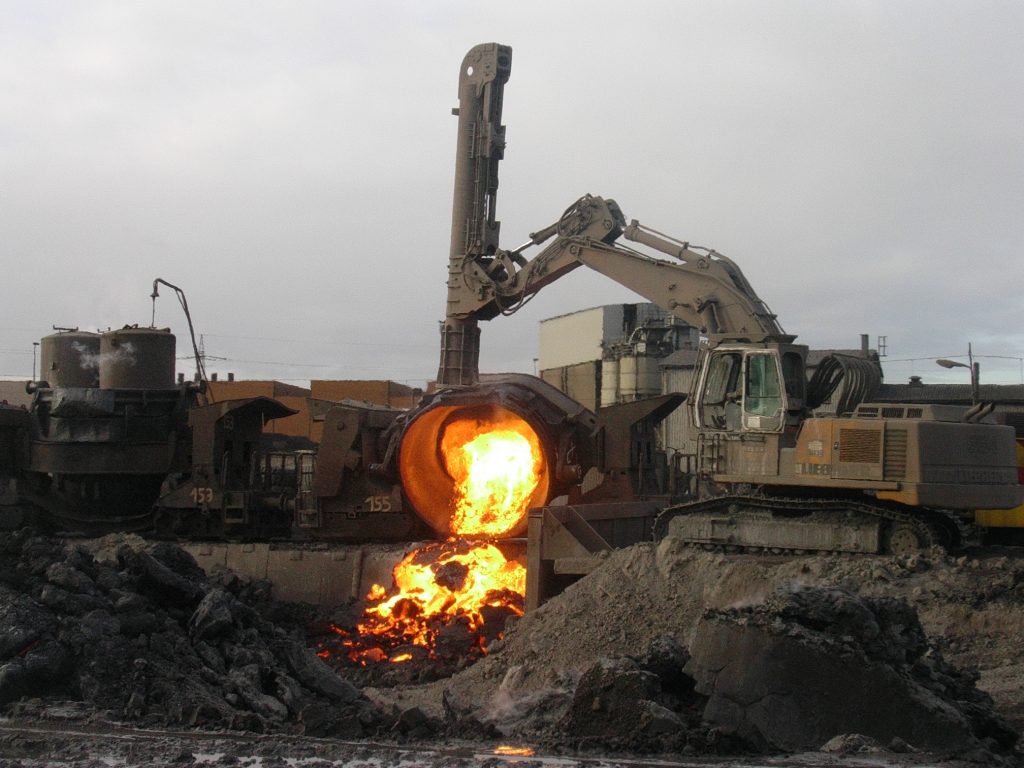 A large vat pours red-hot steel slag into a pile to cool.