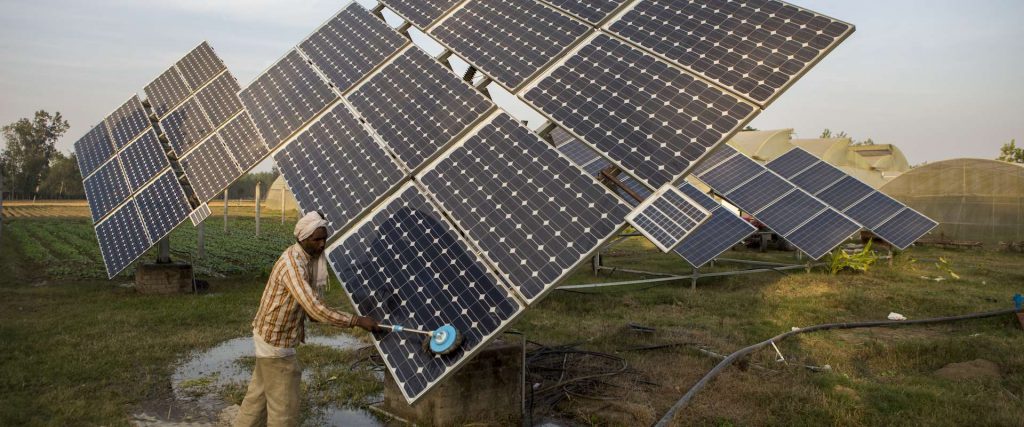 An Indian man cleans a solar panel.