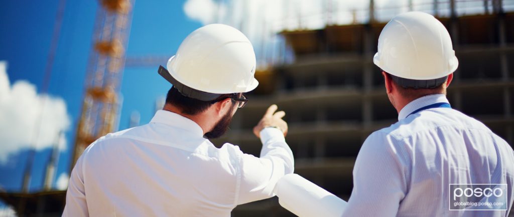 Two workers having a discussion while looking at a construction site.
