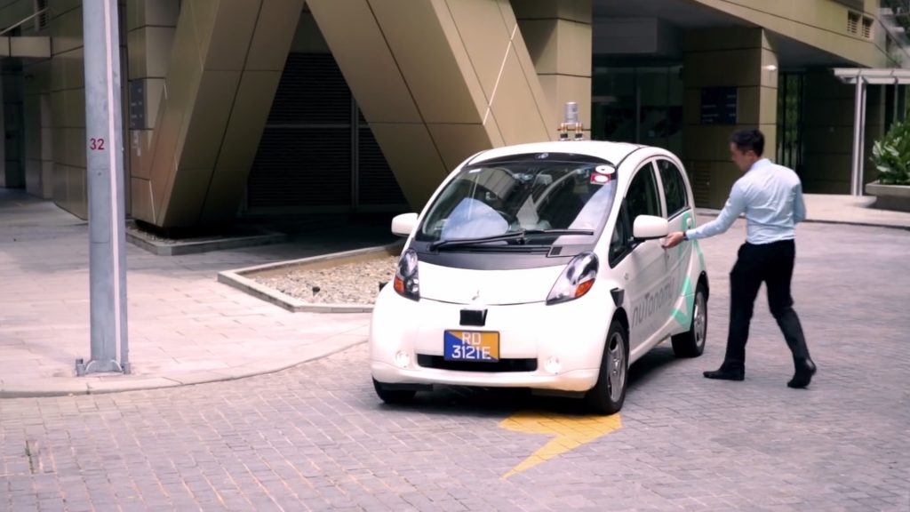 A man is opening the door to one of nuTonomy’s autonomous taxis in Singapore.