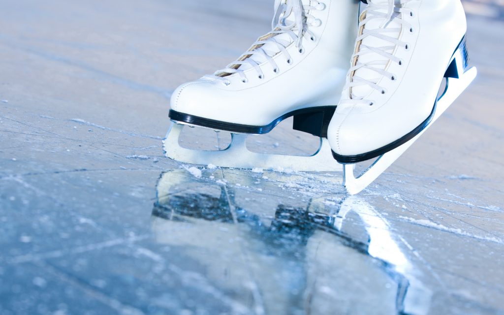 A pair of white figure skates on ice. 