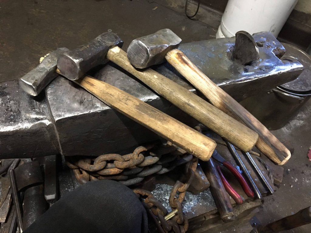 Three hammers resting on a blacksmith’s anvil.