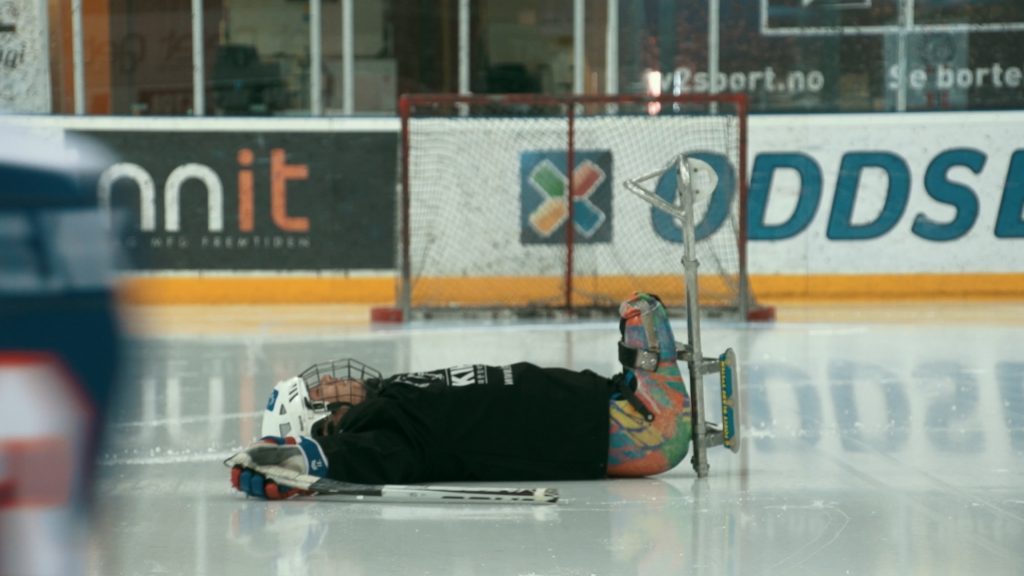 One player on the para ice hockey team lying on his back on the ice.