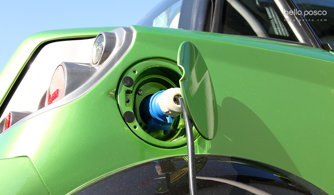 초록색 자동차의 열린 주유구에 주유가 되고 있는 모습