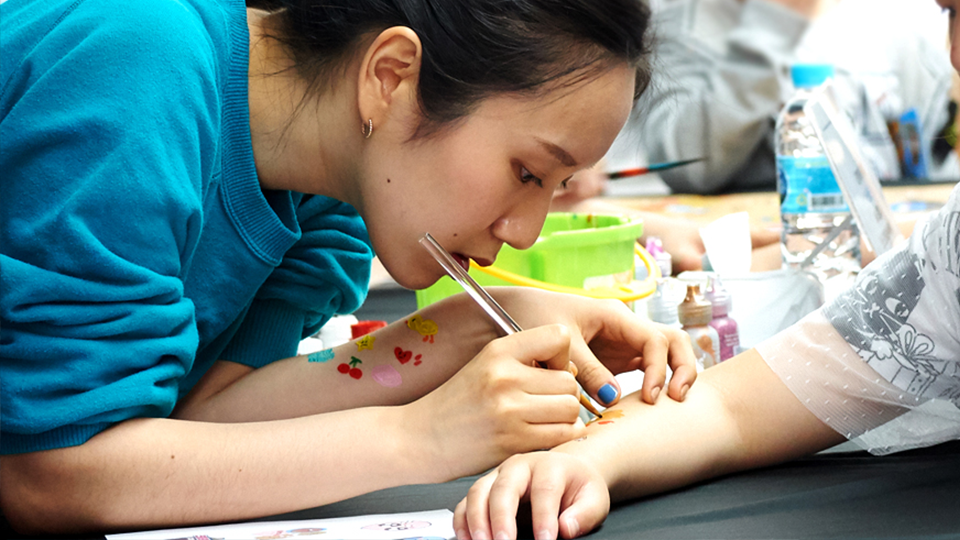 페이스 페인팅 도우미로 참가한 이솜이씨가 부스를 찾은 어린이의 팔에 그림을 그려주고 있다. 