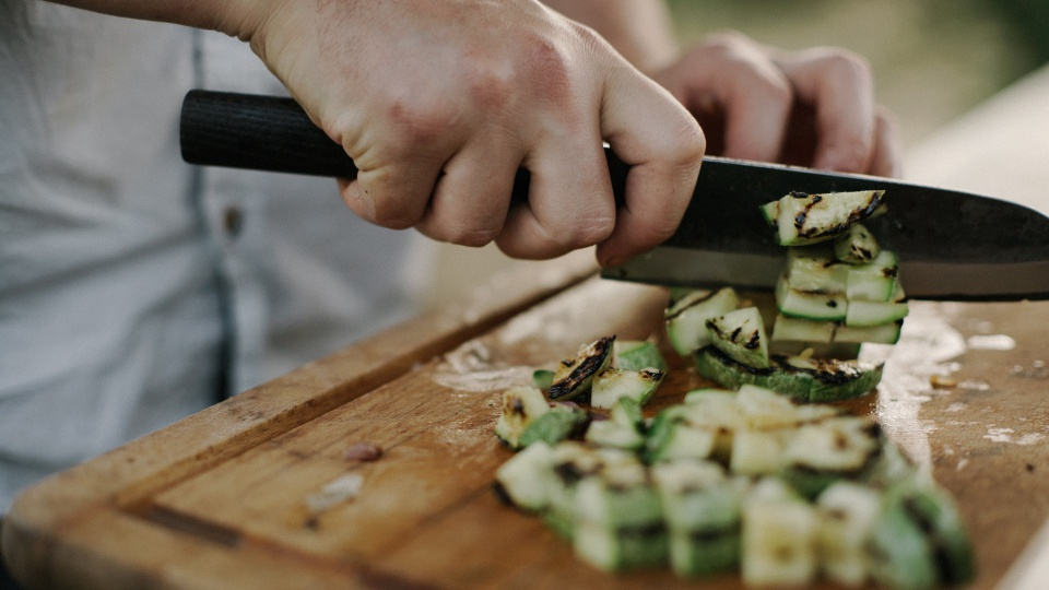 나무 도마 위에 구운 야채를 셰프가 칼로 자르고 있다. 출처: Unsplash