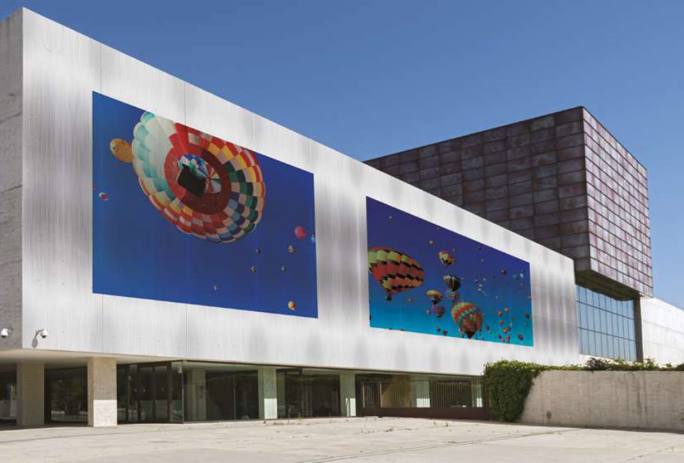 직사각형의 멋지 건물 외벽에 다양한 색상의 열기구가 프린팅 되어있는 이미지