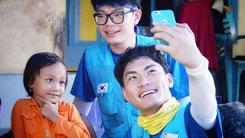 봉사단원과 현지 아이가 즐겁게 핸드폰으로 사진을 찍고 있다.