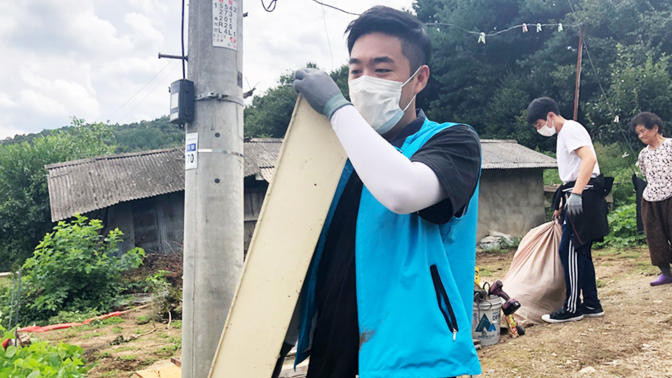 포스코건설 해피빌더- 봉사단원이 마스크를 쓰고 물건을 나르는 모습