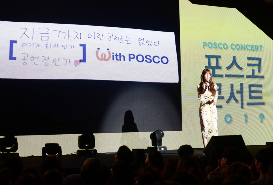 포스코콘서트 'Hope_Full' 무대에서 MC가 With POSCO 앞의 빈칸 채우기 이벤트를 진행하고 있다. 스크린에는 "지금까지 이런 콘서트는 없었다. 여기가 회사인가 공연장인가"라는 재치있는 문구가 나타나 있다.