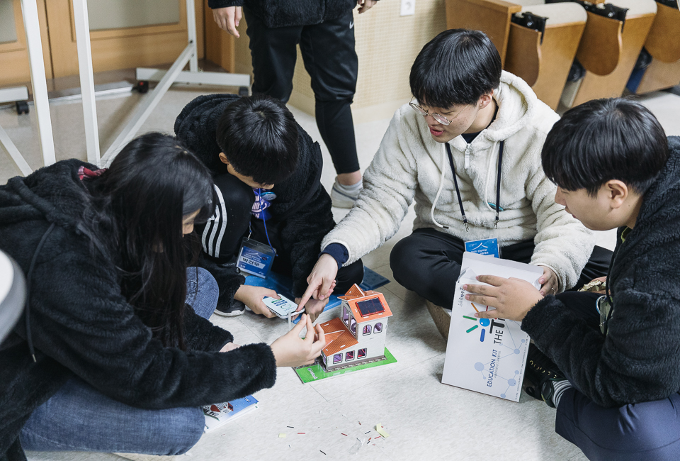 학생들이 머리를 맞대고 이리저리 맞춰보고 휴대폰을 연결해 작동시켜 보고있다.