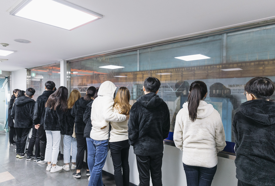 옹기종기 모여 창 넘어 작업현장을 보고 있는 학생들