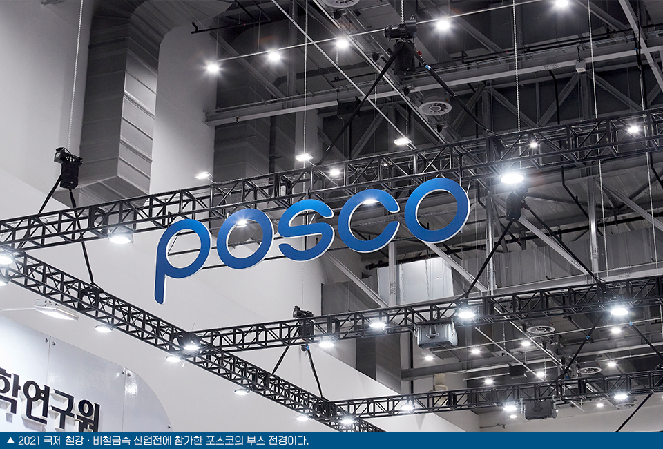 전시회에서 포스코의 부스 천장쪽을 찍은 모습으로 POSCO로고가 크게 설치되어있다. 이미지 하단에는 ▲ 2021 국제 철강 • 비철금속 산업전에 참가한 포스코의 부스 전경이다. 라고 쓰여져 있다.
