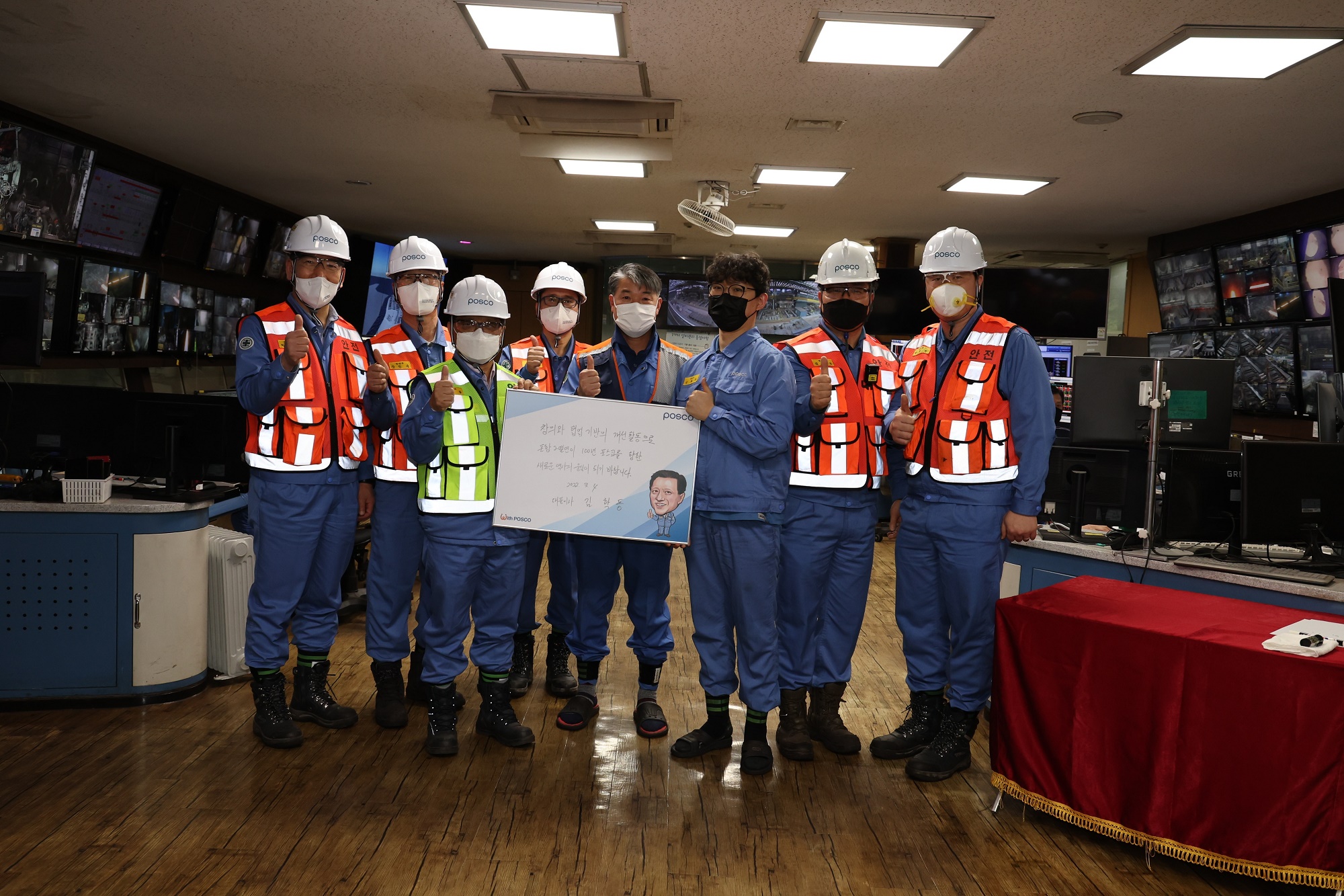 김학동포스코 부회장과 2열연 공장 직원들의 기념사진 촬영 모습으로, 격려인사를 담은 현판을 전달하고 있다. 