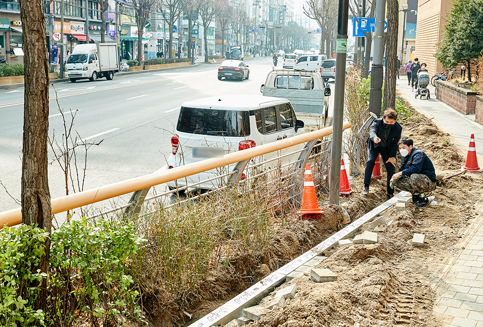 포스맥 배리어를 시공하기 위해 보도블록이 파헤쳐져 있고, 그 속에서 관계자들이 의논하고 있는 모습이다. 