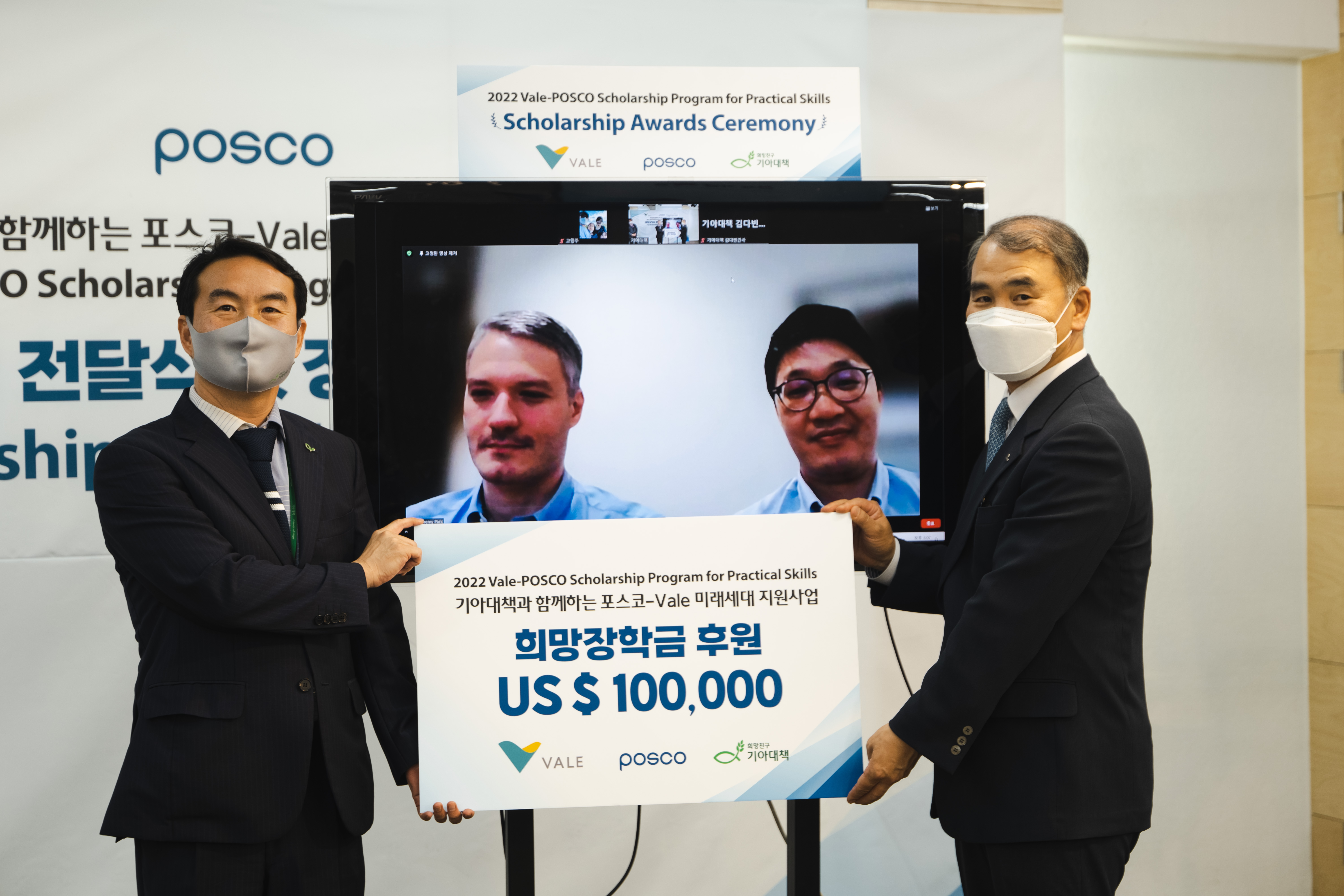 2022 vale-POSCO Scholarship Program for Practical Skills  기아대책과 함께하는 포스코-Vale 미래세대 지원사업 희망장학금 후원 US &100,000 팻말을 들은  왼쪽 기아대책 김태일 사회공헌파트너십부문장과 오른쪽 발레 루이스 알케레스 도쿄지사 판매총괄 발레 박재현 차장이 사진을 찍고있다.