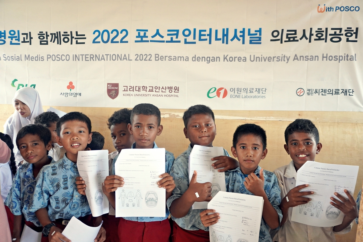 고대안산변원과 함께하는 2022 포스코인터내셔널 의료사회공헌 현수막 앞에 모여 신처검사서를 들고 있는 현직 아이들의 모습이다.