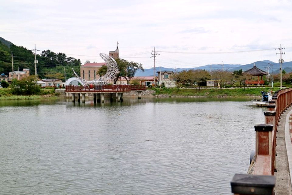시골 한적한 항구 초입에 물고기 조형물이 설치되어 있는 모습이다