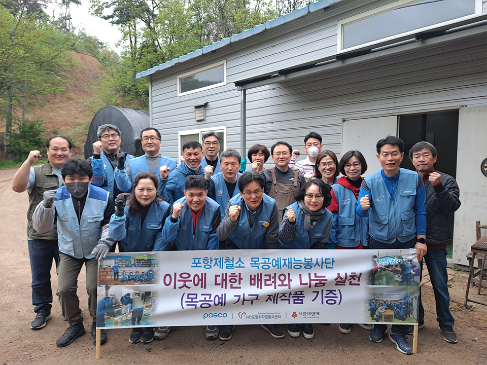 ▲ 기계면에 위치한 공방에서 목공예봉사단이 재능나눔을 실천하고 단체 기념사진을 찍고 있다. 