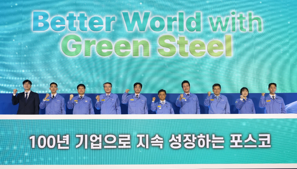 ▲ ‘Better World with Green Steel’이라고 적힌 스크린 앞에 포스코 김학동 대표이사 부회장을 비롯한 9명의 관계자들이 화이팅을 외치며 기념 사진을 찍고 있다. 단상 앞 스크린에는 100년 기업으로 지속 성장하는 포스코라고 적혀있다.