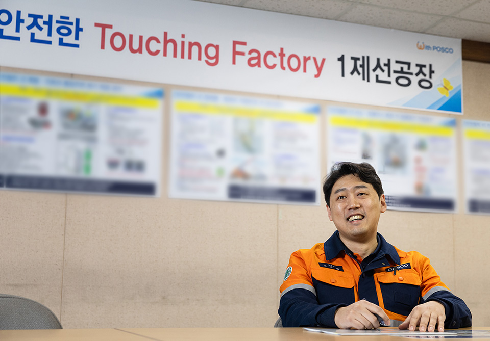 안전한 Touching Factory 1 제선공장 이라고 벽면에 현수막이 붙여져있다. 제선부 이주환이 앉아서 웃으며 인터뷰어를 바라보고 있다. 