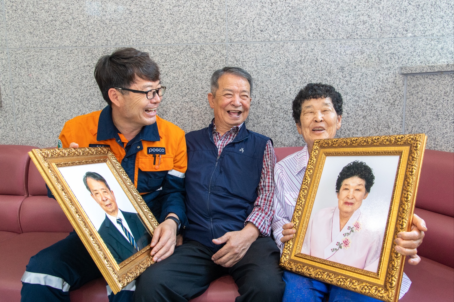 양경식 사진재능봉사단장과 어르신 두 분이 장수사진 액자를 들고 환하게 웃고 있다. 