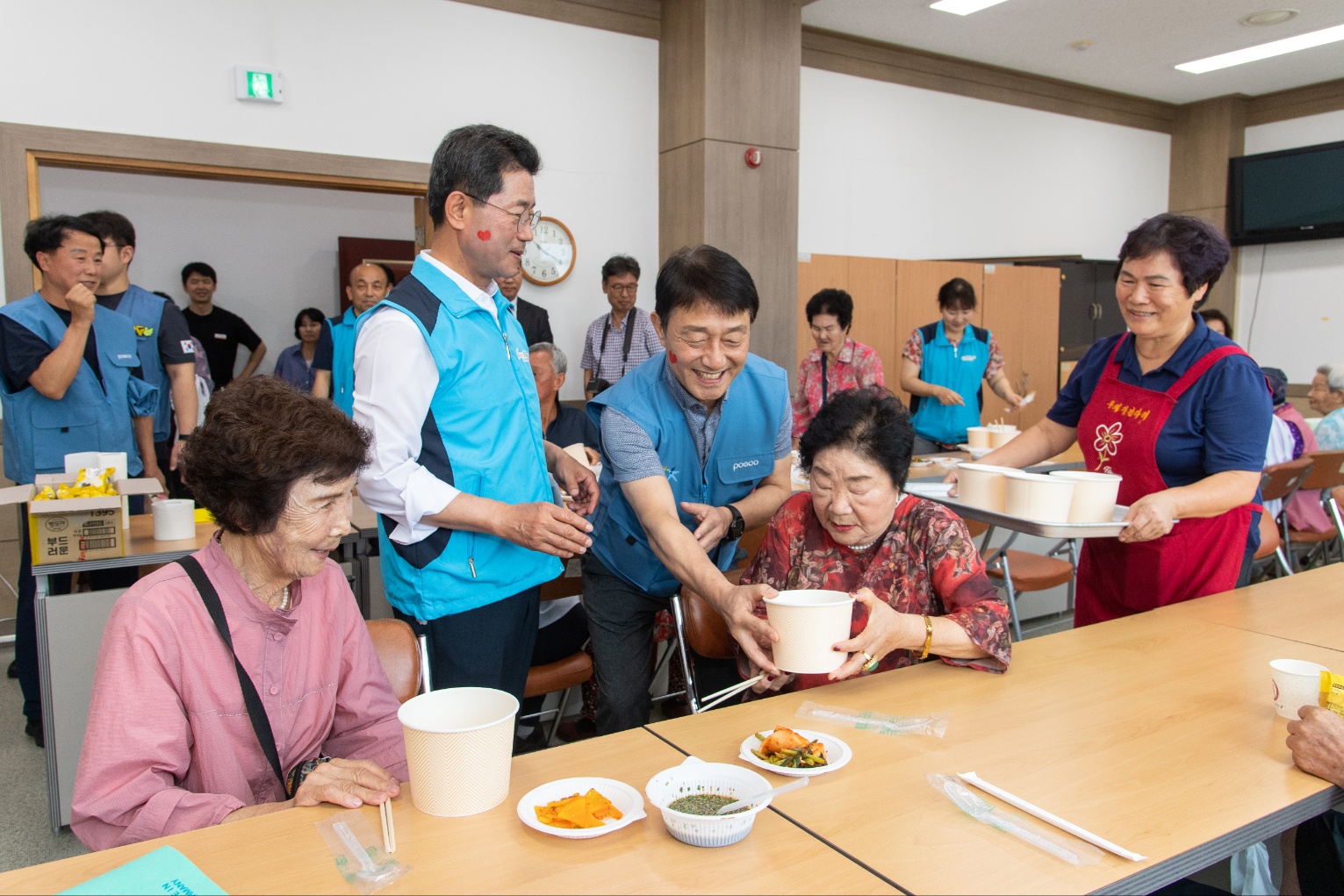 광양제철소 직원들이 지역 어르신들에게 식사가 담긴 그릇을 건네고 있다. 