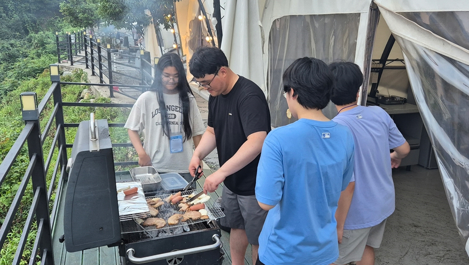 광양제철소가 진행한 1박2일 글램핑 행사에서 직원과 자녀들이 야외에 삼삼오오 모여 고기를 구워 먹고 있다.