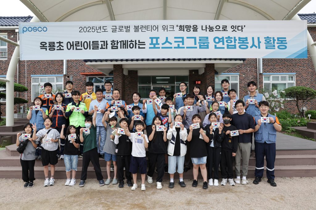 ▲2025년 글로벌 볼런티어 위크를 맞아 장인화 포스코그룹 회장이 광양시 옥룡초등학교 학생들과 함께 전통 한지로 만든 태극기를 들고 단체 사진촬영을 하고 있다. 위에 현수막에는 2025년도 글로벌 볼런티어 위크 '희망을 나눔으로 잇다' 옥룡초 어린이들과 함께하는 포스코그룹 연합봉사 활동 이라고 적혀있다.