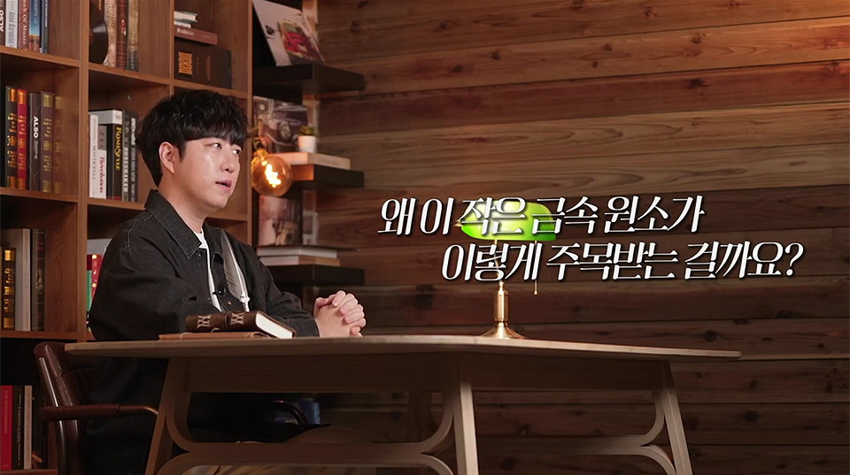 궤도가 서재에 있는 책상에 앉아있고 궤도 앞에 작은 스탠드가 켜져 있으며, 사진에는 "왜 이 작은 금속 원소가 이렇게 주목받는 걸까요?"라는 캡션이 있다.