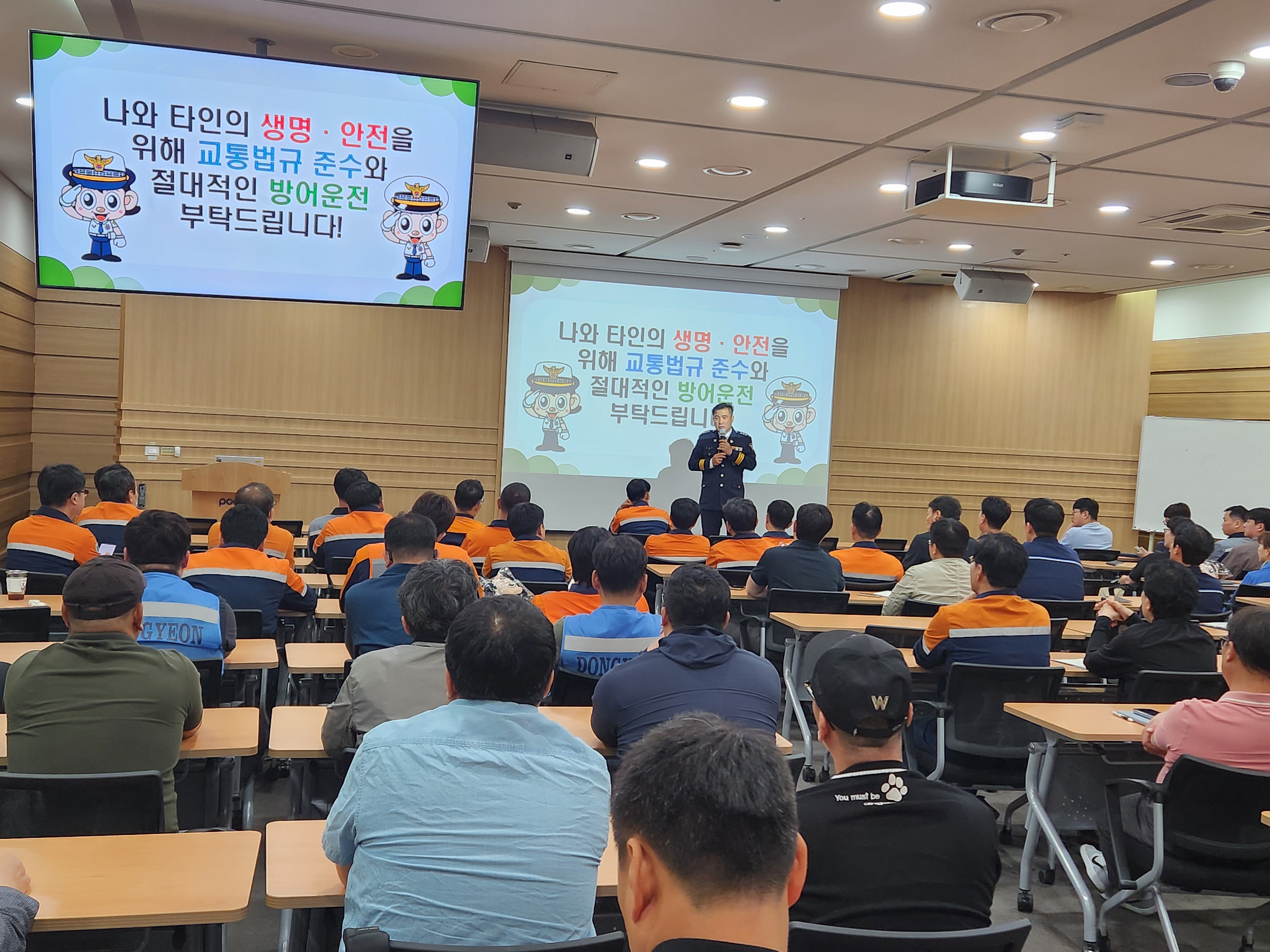▲ 지난 13일, 포스코 포항제철소가 교통안전 특강을 진행하였다. 교육을 듣는 직원들의 뒷모습, 경찰제복을 입은 사람이 앞에서 강의를 하고 있다. 스크린에는 나와 타인의 생명안전을 위해 교통법규 준수와 절대적인 방어운적 부탁드립니다! 라고 쓰여있다.
