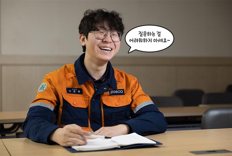 주인공이 노트를 펼쳐놓고 웃고 있다. 말풍선 "질문하는 걸 어려워하지 마세요~"