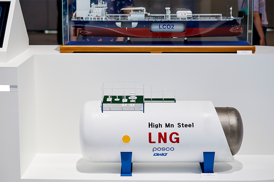▲ 포스코 고망간강으로 제작된 LNG 저장탱크 모형. 둥근 배관 모양 위에 high Mn Steel LNG POSCO라고 쓰여있다. 위에는 LCO2 운반선 모형이 있다.