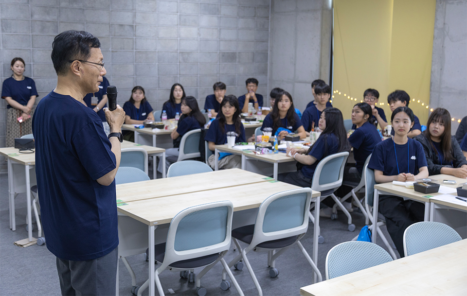 (사진1) 포항시 다문화가정 및 취약계층 자녀들과 한동대 재학생 멘토 총 48명이 함께한 ‘포어스(FOURS)’ 진로캠프 현장 모습 , 마이크를 든 선생님이 강의 중이며 대학생 멘토와 청소년 멘티들이 집중해서 바라보고 있다.