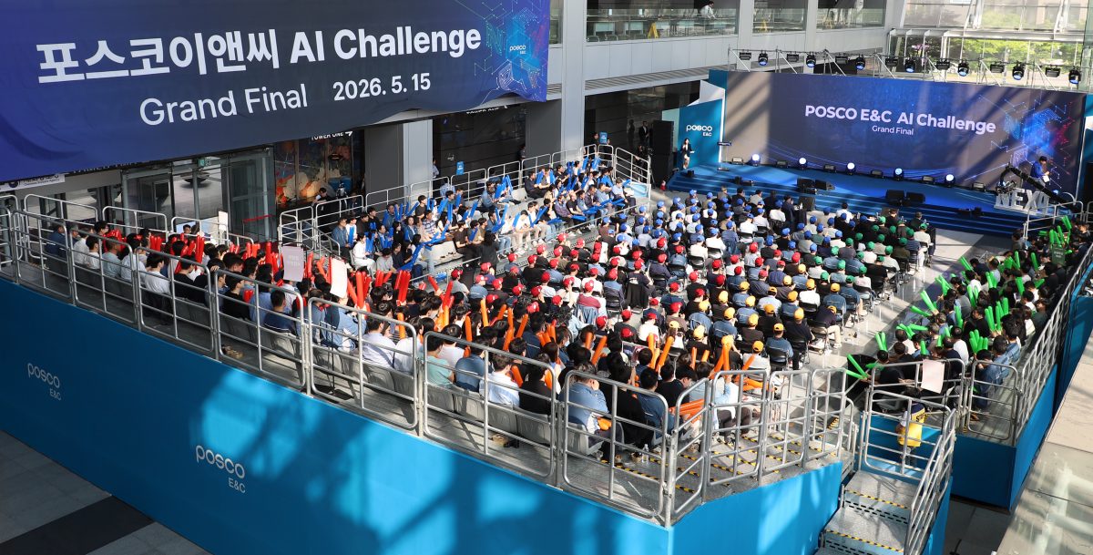 실내 대형 홀에서 열린 '포스코이앤씨 AI 챌린지 그랜드 파이널' 행사 전경. 파란색과 흰색으로 꾸며진 무대와 그 앞의 계단식 객석에 수많은 참가자가 앉아 있으며, 일부 참가자들은 응원 도구를 들고 행사에 집중하고 있다.