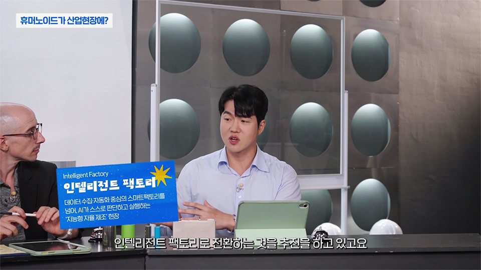 포스코 인텔리전트 팩토리를 설명하는 윤주성 대리 사진 / 상단 제목 : 휴머노이드가 산업현장에? / 왼쪽 그래픽 설명 : 인텔리전트 팩토리:데이터 수집, 자동화 중심의 스마트팩토리를 넘어, AI가 스스로 판단하고 실행하는 '지능형 자율제조' 현장 /하단 자막 : 인텔리전트 팩토리로 전환하는 것을 추진을 하고 있고요