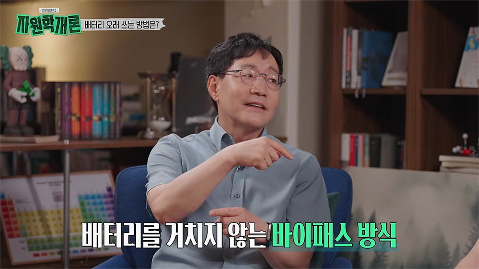 김범준 교수가 손가락으로 가리키며 배터리 사용법을 설명하고 있다. 상단에 ‘배터리 오래 쓰는 방법은?’이라는 제목이 있고, 하단에는 ‘배터리를 거치지 않는 바이패스 방식’이라는 문구가 크게 표시되어 있다.